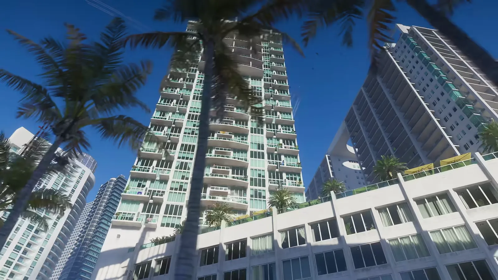 500 Brickell in GTA VI: Low-angle view up at Tequesta high-rises, with a white podium bridge with an oval cutout between the towers at right.