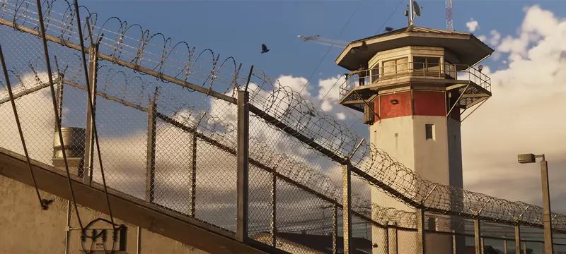 Leonida Penitentiary in GTA VI: A prison lookout tower rises behind razor-wire fencing at the Leonida Penitentiary.